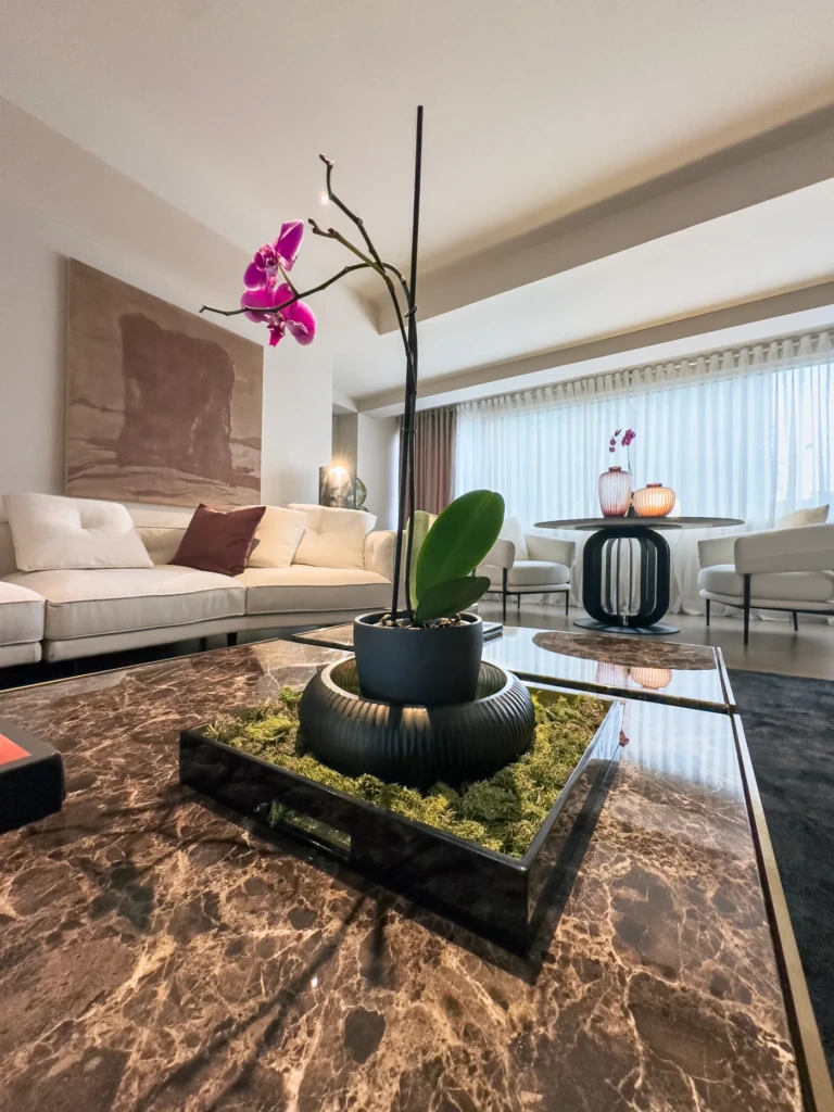 Sala del showroom de STAAD HOME con mesa de marmol, orquidea y mobiliario contemporaneo